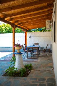 a patio with a table and chairs under a wooden roof at Ektoras House in Platamonas