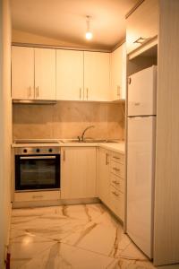a kitchen with white cabinets and a sink and a refrigerator at Ektoras House in Platamonas