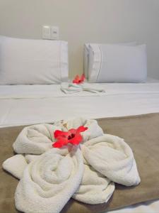 a white towel with red flowers on a bed at Pousada do Trinta in Fernando de Noronha
