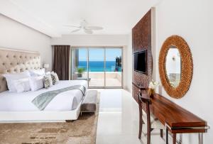 a bedroom with a bed and a desk and a mirror at Garza Blanca Resort & Spa Los Cabos in El Bedito +106 photos