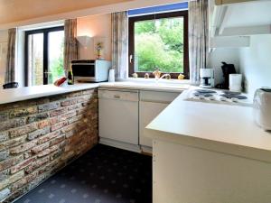eine Küche mit weißen Arbeitsflächen und einer Ziegelwand in der Unterkunft Cozy bungalow with large enclosed garden in Baillamont