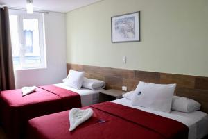 ein Hotelzimmer mit zwei Betten mit roter Bettwäsche in der Unterkunft Hotel Teresita in Puebla