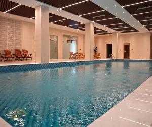 a large swimming pool with blue water in a building at Anbar International Hotel in Kumaysh