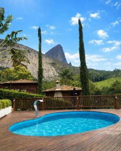 a swimming pool in a yard with a mountain in the background at Pousada Peterle in Domingos Martins