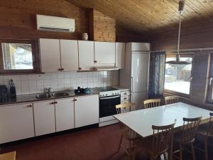 a kitchen with white cabinets and a table with chairs at Skutstuga 6 - Gruvbacken Huså in Järpen