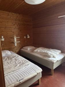 two beds in a room with wooden walls at Skutstuga 6 - Gruvbacken Huså in Järpen