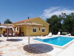 a swimming pool with an umbrella and a house at Detached house at country side fenced in Vodnjan