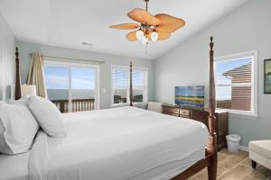 a bedroom with a white bed and a television at Didjeridu West by Emerald Isle Realty in Emerald Isle