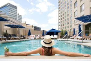 a woman in a hat sitting in a swimming pool at The Ritz-Carlton, Dallas in Dallas
