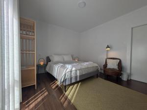 a white bedroom with a bed and a chair at Beach Avenue Suite in Apúlia