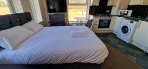 a bedroom with a white bed and a kitchen at SELF CHECK-IN PENTHOUSE APARTMENT in HALIFAX CENTRE in Halifax