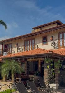 a house with a deck and chairs on a patio at Casa Melville Hospedagem - Sua Casa de Alto Padrão no Coração de Ubatuba! in Ubatuba