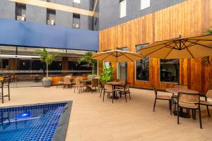 a patio with tables and chairs with umbrellas and a pool at Amazon Park Hotel in Belém