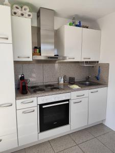a kitchen with white cabinets and a stove top oven at Piccolo gioiello rustico in Losone