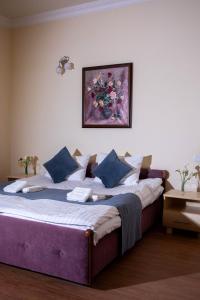a large bed with blue pillows and a painting on the wall at Casanova Inn - Boutique Hotel in Dilijan