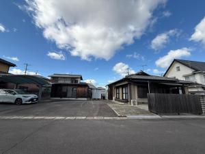 a parking lot with two houses and a car at あかねや in Marugame
