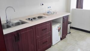 a kitchen counter with a sink and a dishwasher at Impress Hotel in Addis Ababa