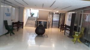 a hallway with a vase on the floor and chairs at Impress Hotel in Addis Ababa