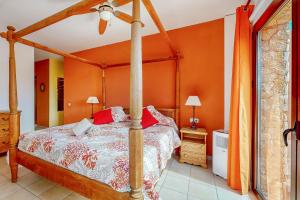 a bedroom with a canopy bed with an orange wall at Villa Cora - Traumvilla mit privatem Tennisplatz & beheiztem Pool in Triquivijate +47 photos