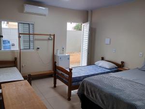 a bedroom with two beds and an open window at Pousada Zero Três - 03 in Chapada dos Guimarães
