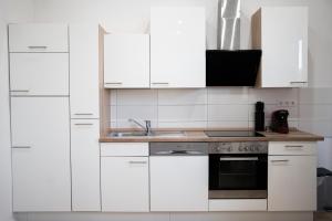 a kitchen with white cabinets and a sink at Design Apartment - Solingen-Mitte - Balkon - BRIGHT Collection in Solingen