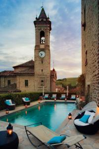 a building with a clock tower and a swimming pool at Hotel Castello Di Sinio in Sinio