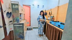 a woman is standing in a kitchen at Hanki Guest House syariah in Gadok 1