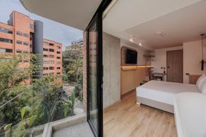 a bedroom with a bed and a large window at Lomm By Somos The Group in Medellín +171 photos