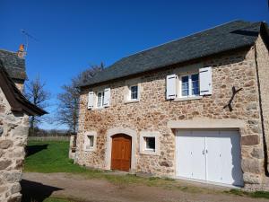 an old stone building with two white garage doors at La Grange de Noëlie in Lanuéjouls-et-Privezac