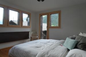 a bedroom with a white bed and windows at Casa Castanea in Breiten