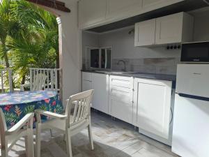 a kitchen with white cabinets and a table and chairs at Just in paradise in Baie Nettle