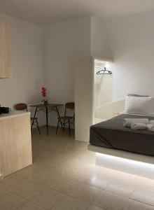 a bedroom with a bed and a table with chairs at LEIVADAROS apartments in Perissa