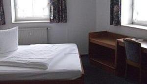 a bedroom with a bed and a desk and a window at Hotel am Hexenturm in Jülich