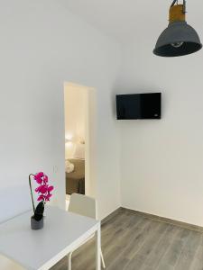 a white dining room with a white table and a tv on a wall at LEIVADAROS apartments in Perissa
