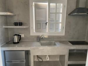 a kitchen counter with a sink and a window at LEIVADAROS apartments in Perissa +46 photos
