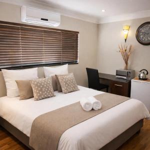 a bedroom with a large white bed with a desk at Caesars Place Guest House in Kathu