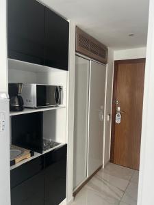 a small kitchen with a microwave and a door at Flat Costa Mar in Recife