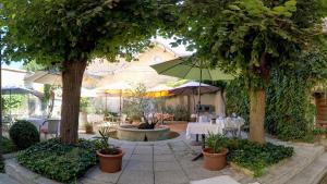 een patio met een tafel en stoelen en een parasol bij Hotel de Bordeaux in Pons