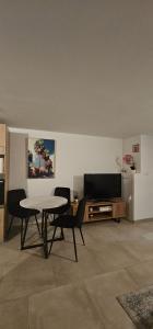 a living room with a table and chairs and a television at La Source in Villers-le-Lac