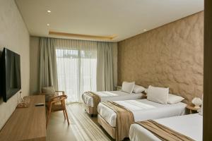 a hotel room with two beds and a television at Howard Johnson Alcántara Boutique Hotel Chacras de Coria, Mendoza in Chacras de Coria