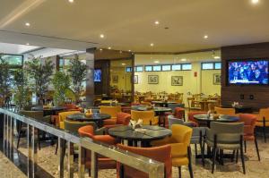 a restaurant with tables and chairs and a flat screen tv at Marante Executive Hotel in Recife