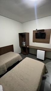 a bedroom with a bed and a flat screen tv at Hotel Luz in Fronteira