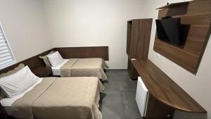 a room with two beds and a flat screen tv at Hotel Luz in Fronteira