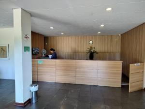 a woman sitting at a reception desk in an office at Piemonte Flat Serra Negra in Serra Negra