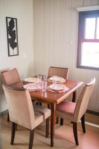 a dining room table with chairs and plates and glasses on it at Chalé 10 min do centro in Gramado
