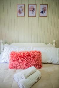 a white bed with a red pile of towels on it at Chalé 10 min do centro in Gramado