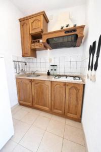 a kitchen with wooden cabinets and a sink at Apartman David in Postira
