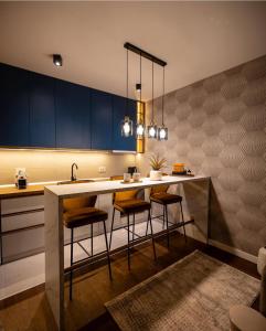 a kitchen with blue cabinets and a counter with stools at Impresia apartments in Kragujevac +3 photos