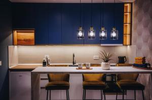 a kitchen with blue cabinets and a counter with stools at Impresia apartments in Kragujevac