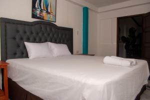 a bedroom with a large white bed with a black headboard at Casa Verde in Granada +1 photo